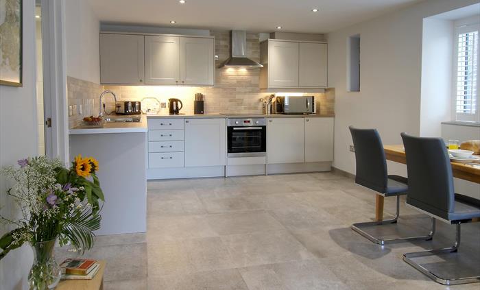 Well-equipped kitchen with pale cabinetry, integrated appliances, and a large dining table set for breakfast.
